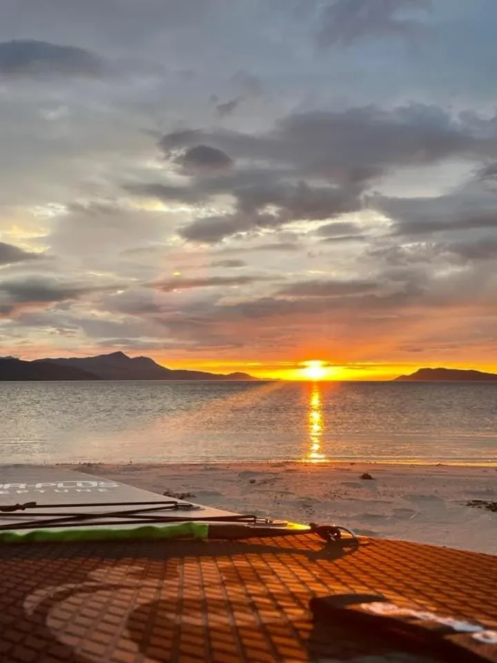 Low sun over the sea seen from a beach with paddle boards